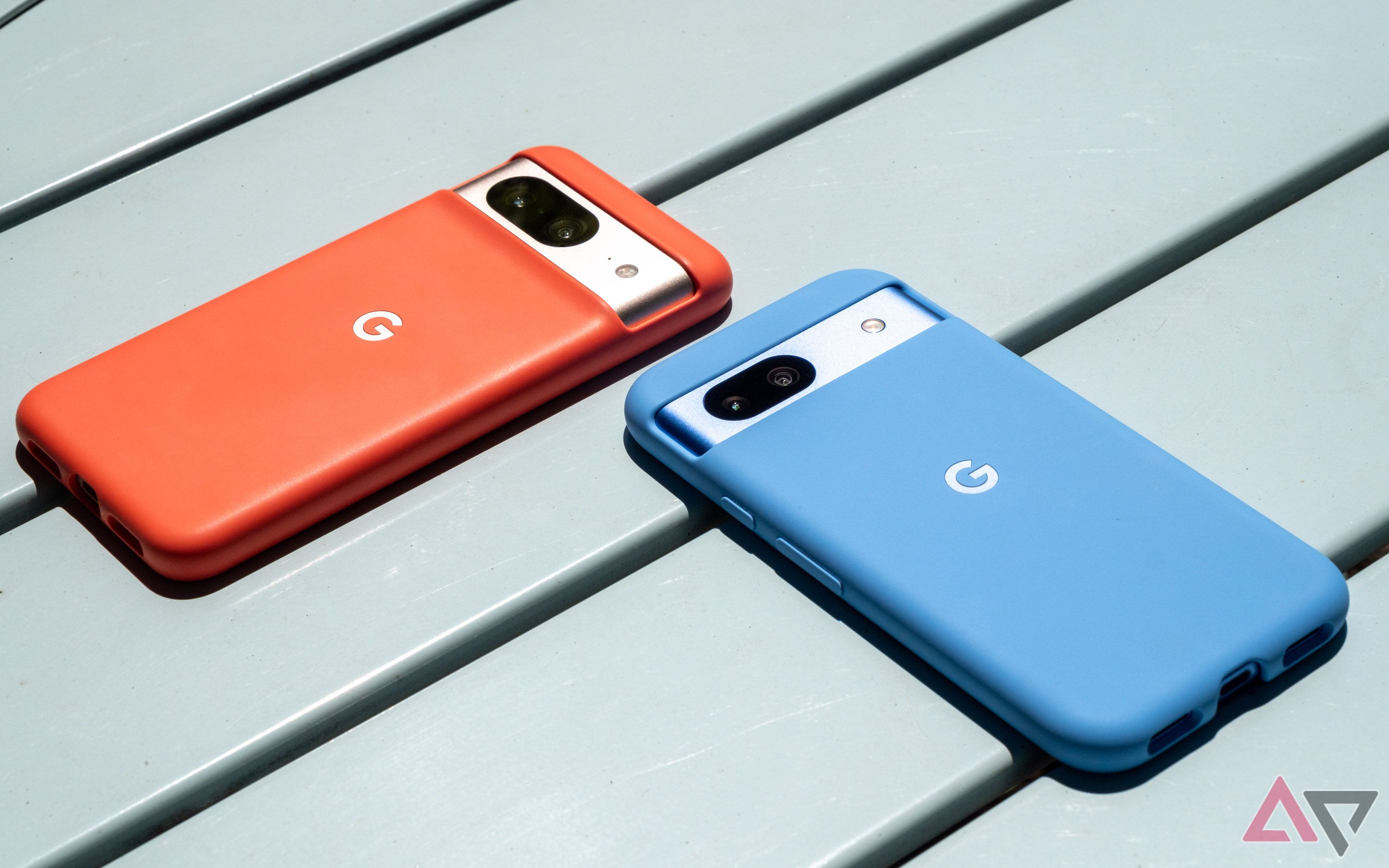 A blue smartphone and an orange smartphone on a metal table