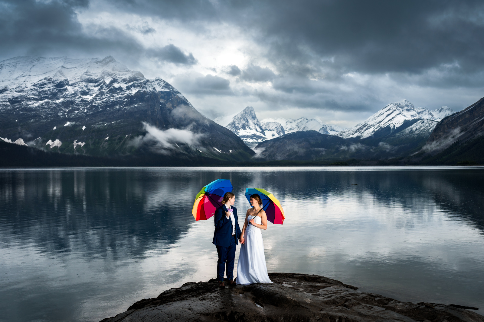 couple under umbrellas in front of epic mountains