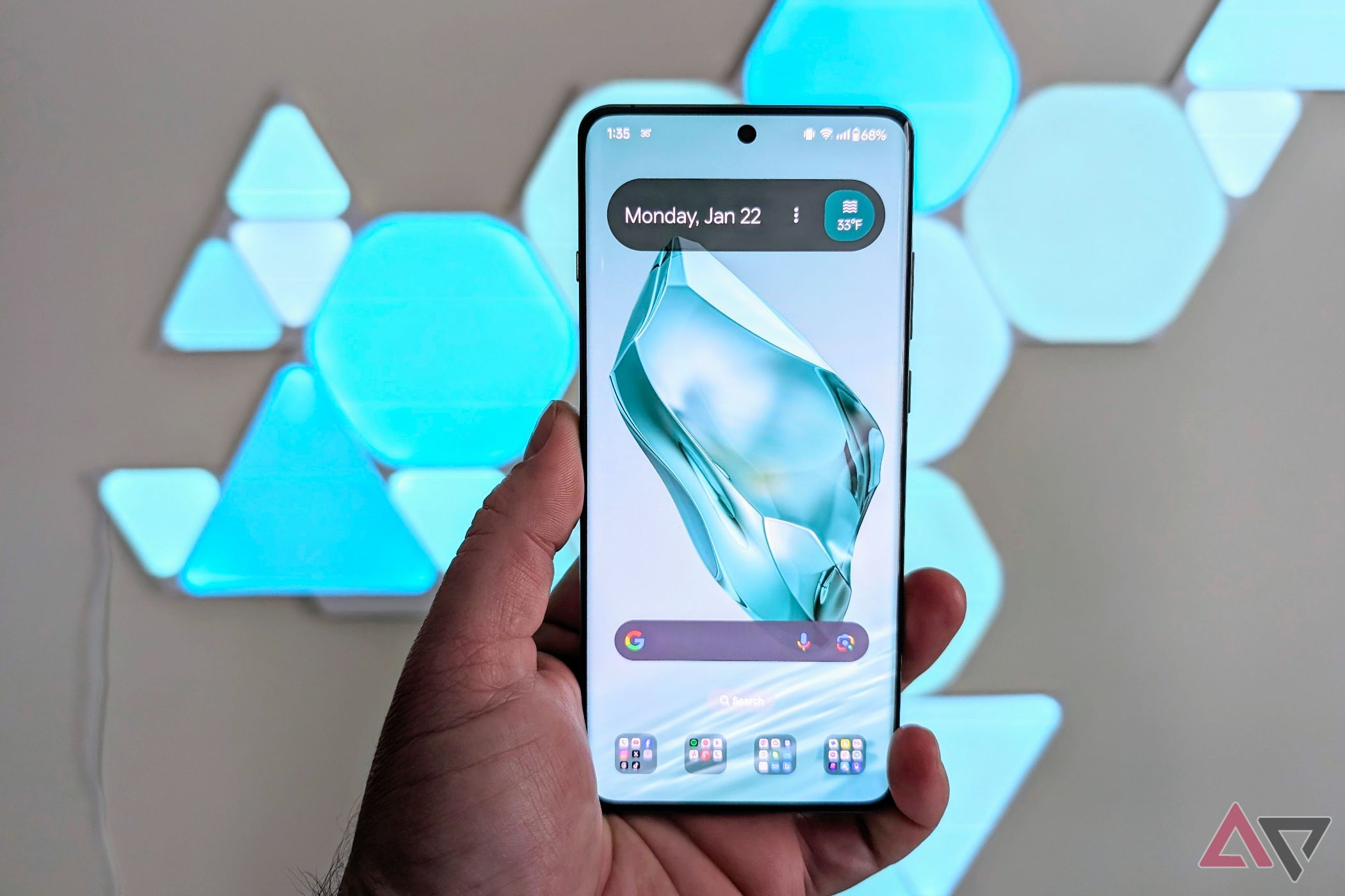 OnePlus 12 showing the homescreen in a hand with light panels behind it