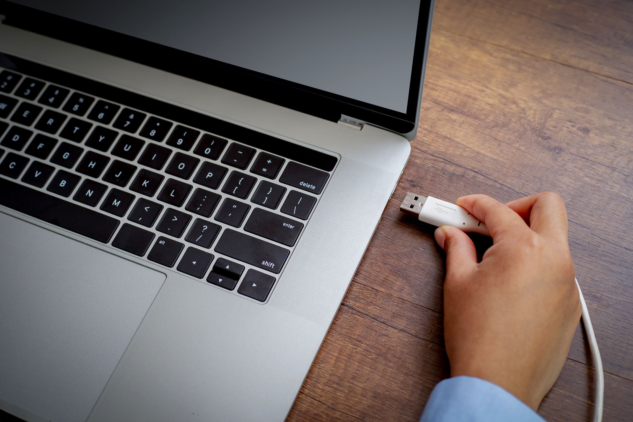 person plugging usb a cable into laptop port