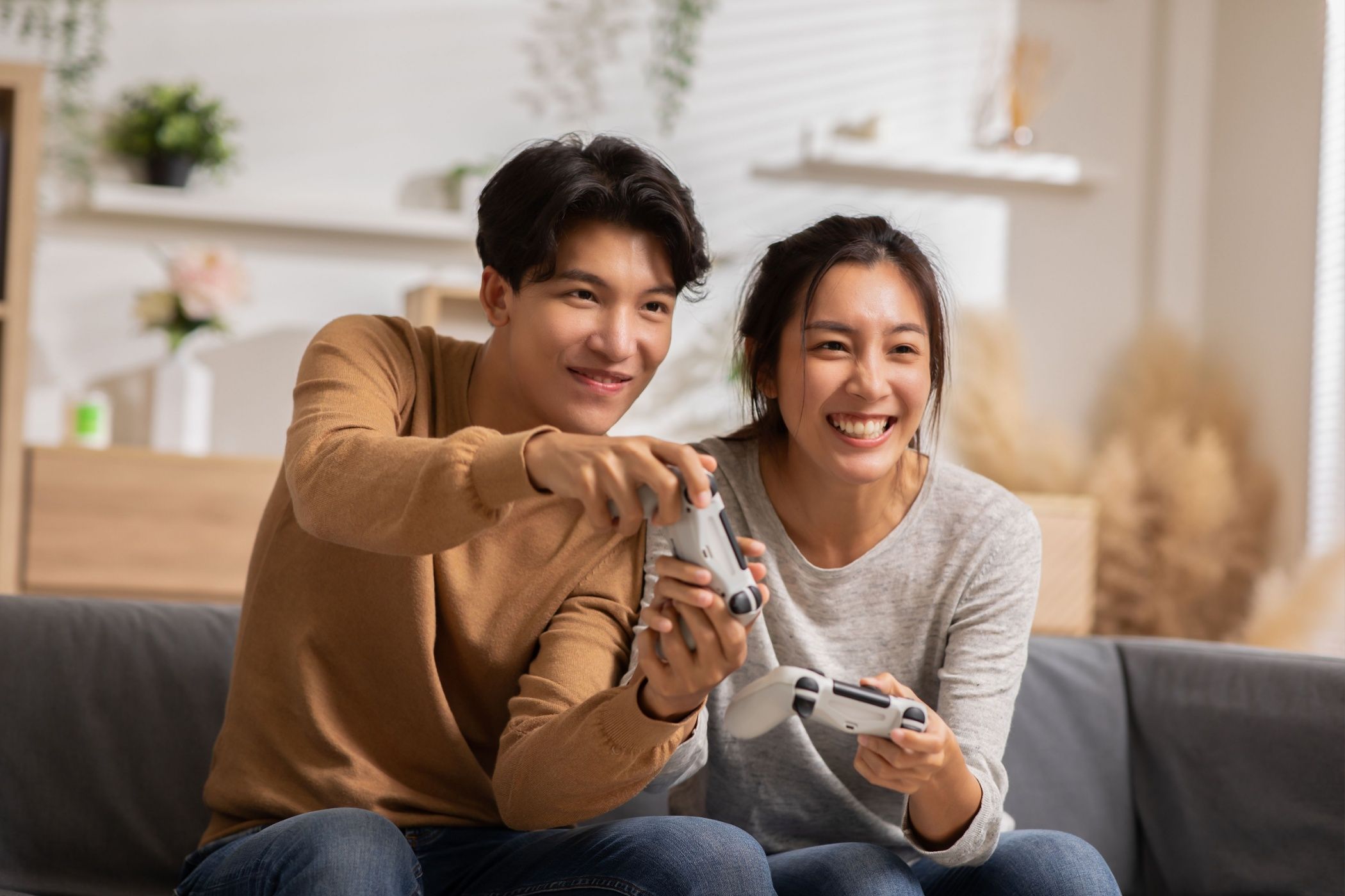 two gamers on a couch with controllers in their hands