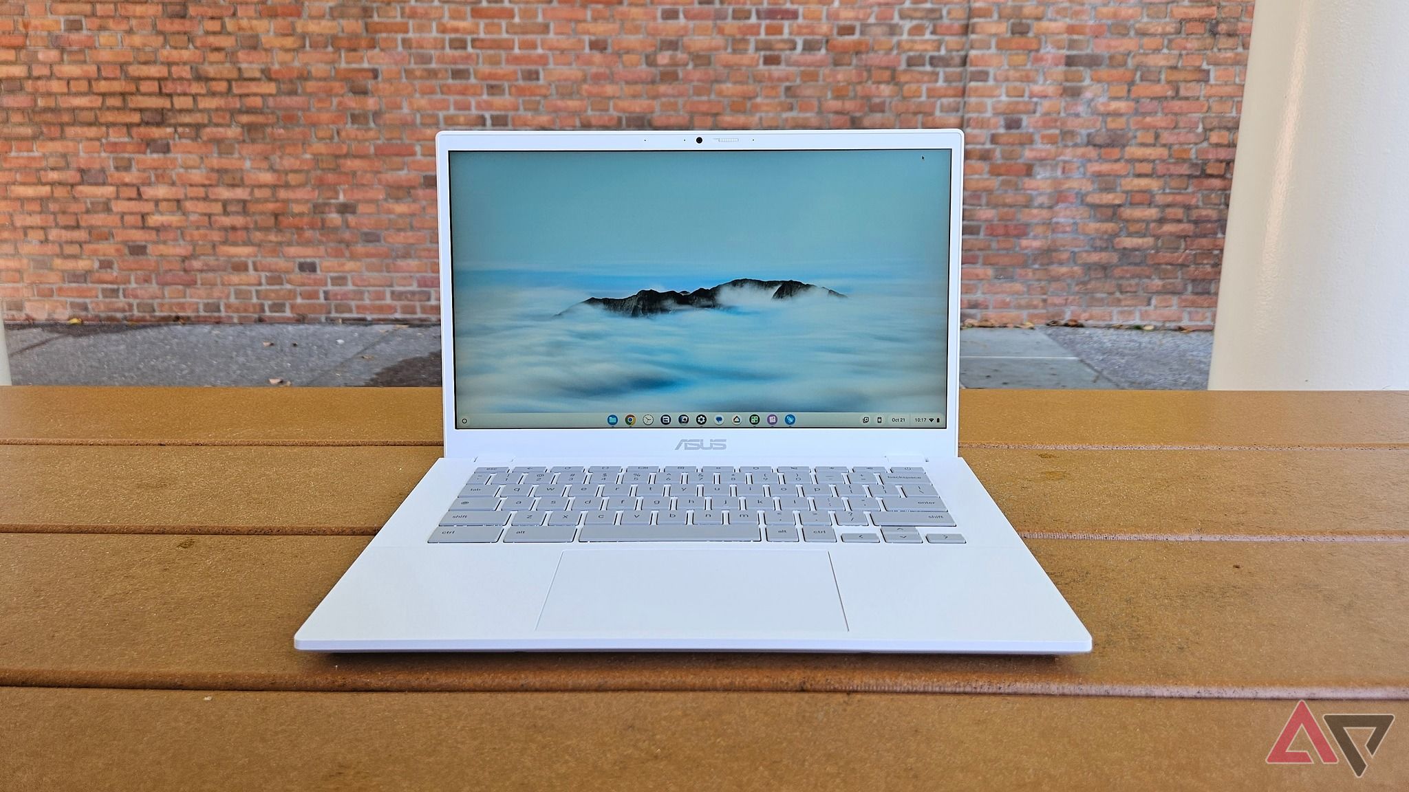 An Asus Chromebook Plus CX34 on top of a table with a brick wall in the background