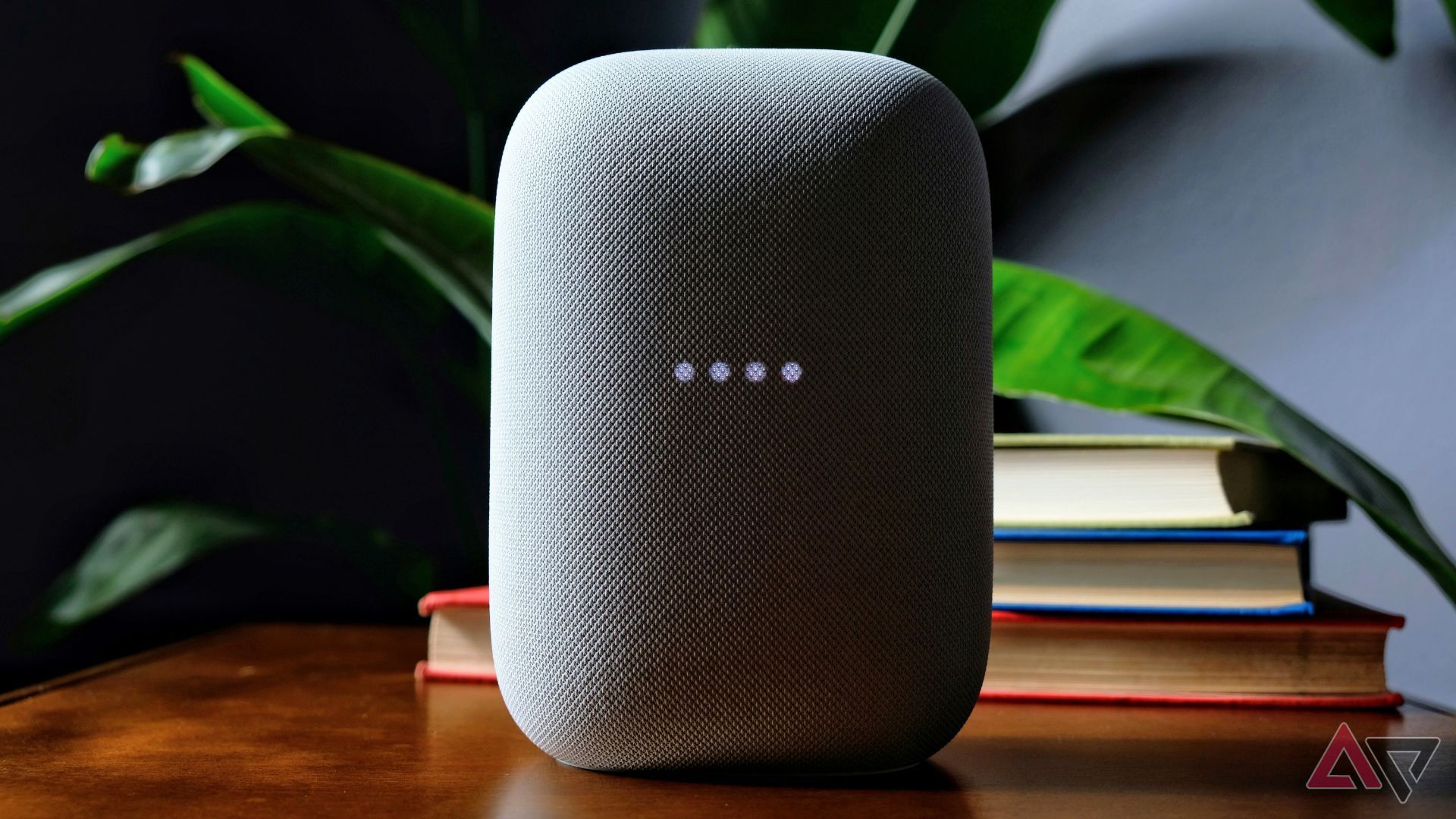 A Nest Audio speaker in front of a stack of books.