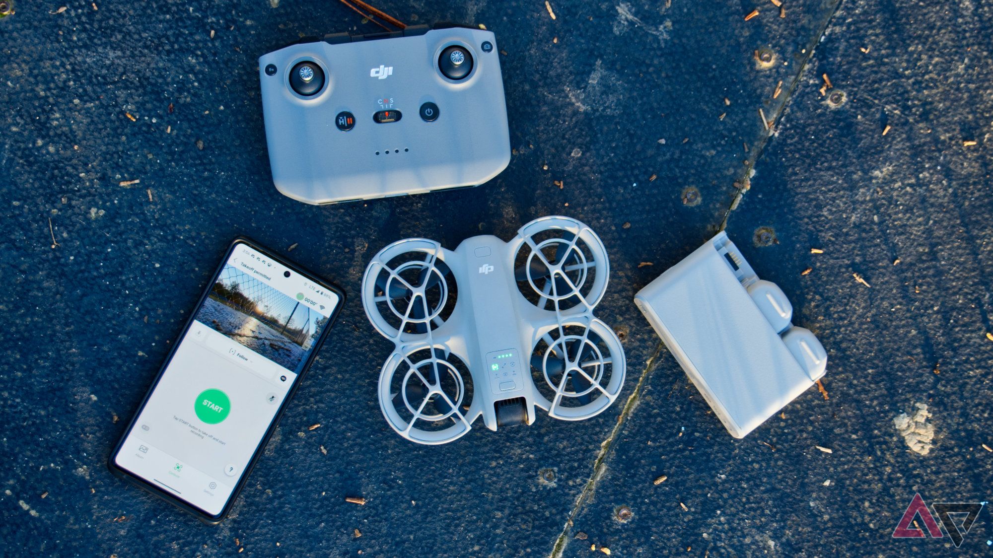 DJI Neo in a flat lay view next to a phone, battery charger, and DJI controller