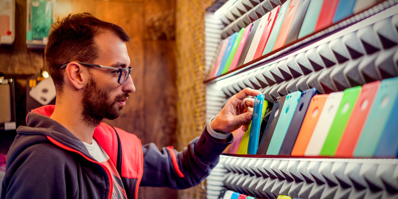 man choosing smartphone case from rack feature