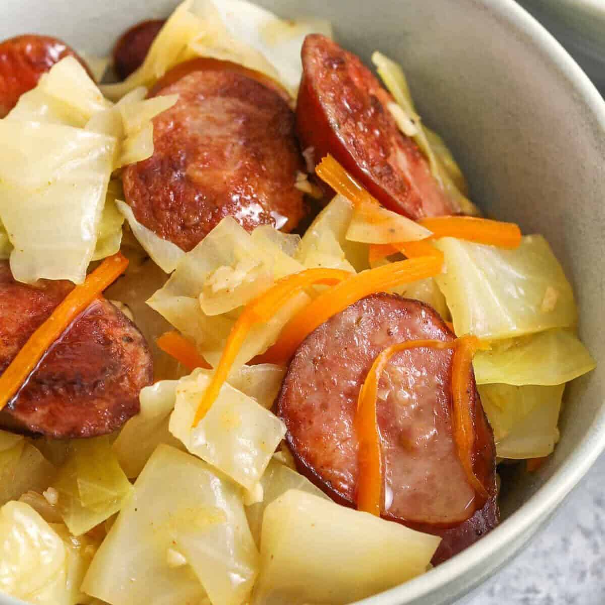 a close up of a cabbage and sausage prepared in a bowl